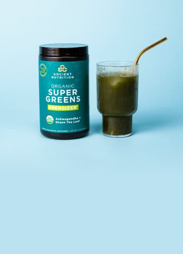 bottle of supergreens next to a glass of green juice